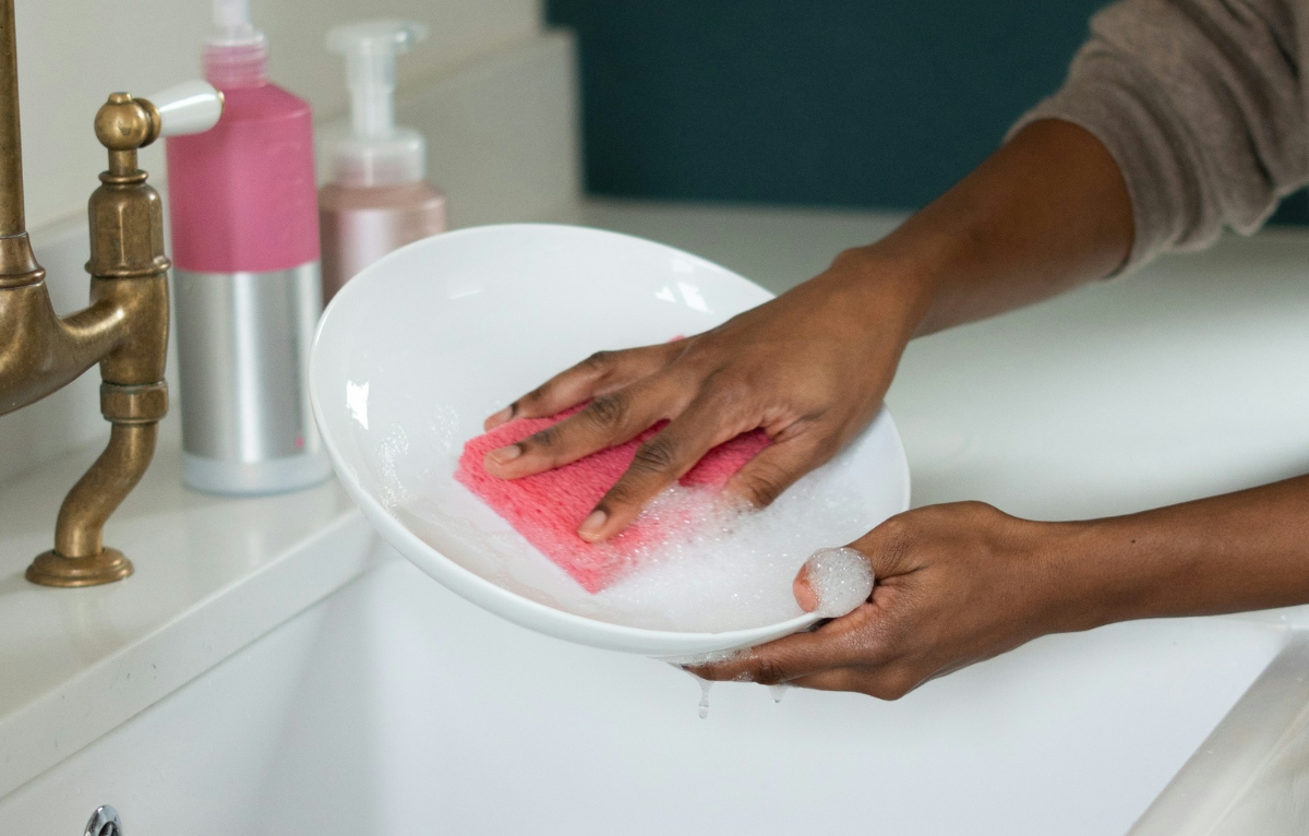 a person washes a dish with a smol sponge