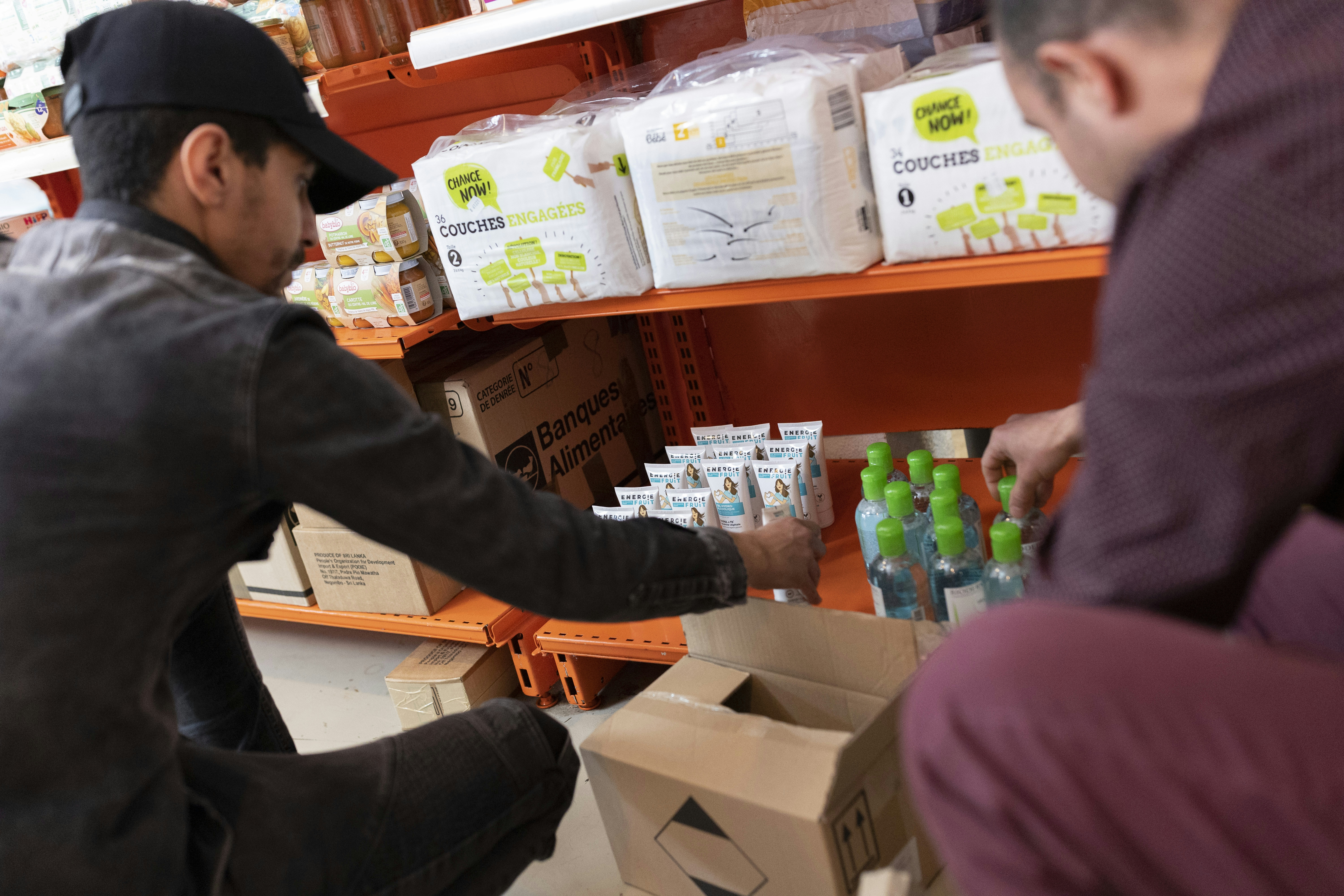 deux bénévoles pour l'Agence du Don en Nature rangeant des produits venant d'une collecte de don sur les étagères d'une épicerie solidaire.