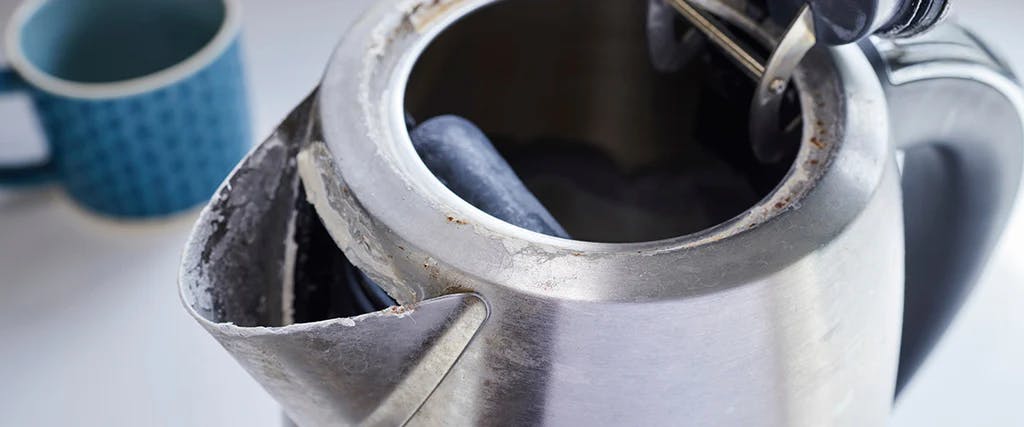 kettle with its lid open, showing limescale build-up over the spout