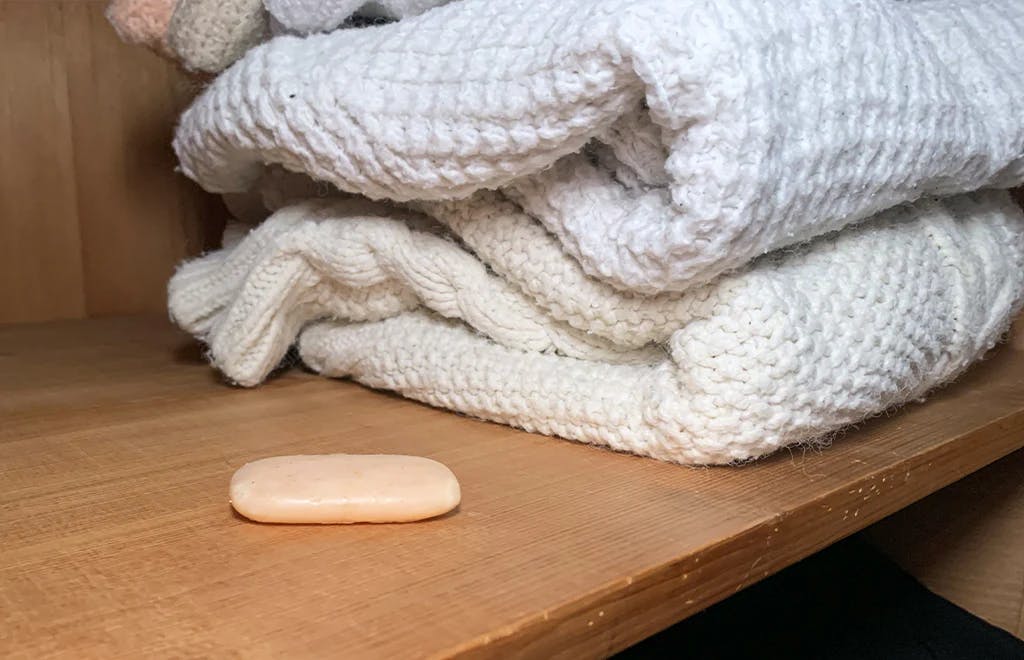 soap on a shelf next to wooly jumpers