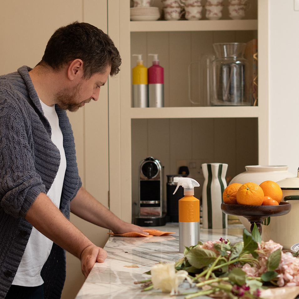 man cleaning a kitchen countertop using smol multi purpose spray