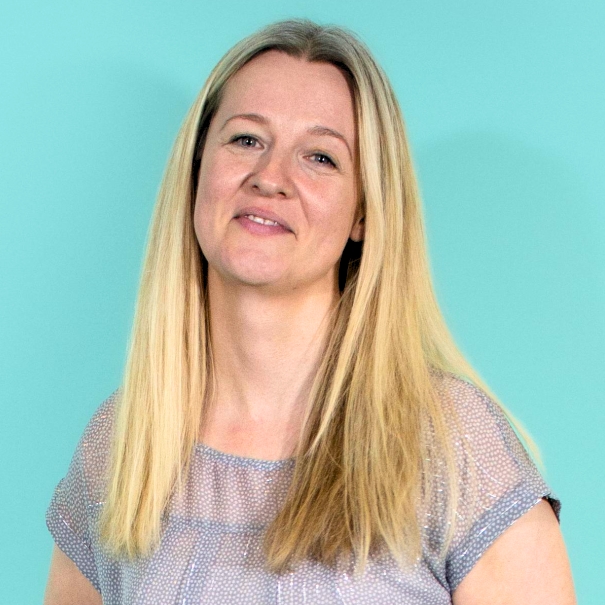 catherine green, a woman with long blonde hair is looking at the camera smiling against a blue green background