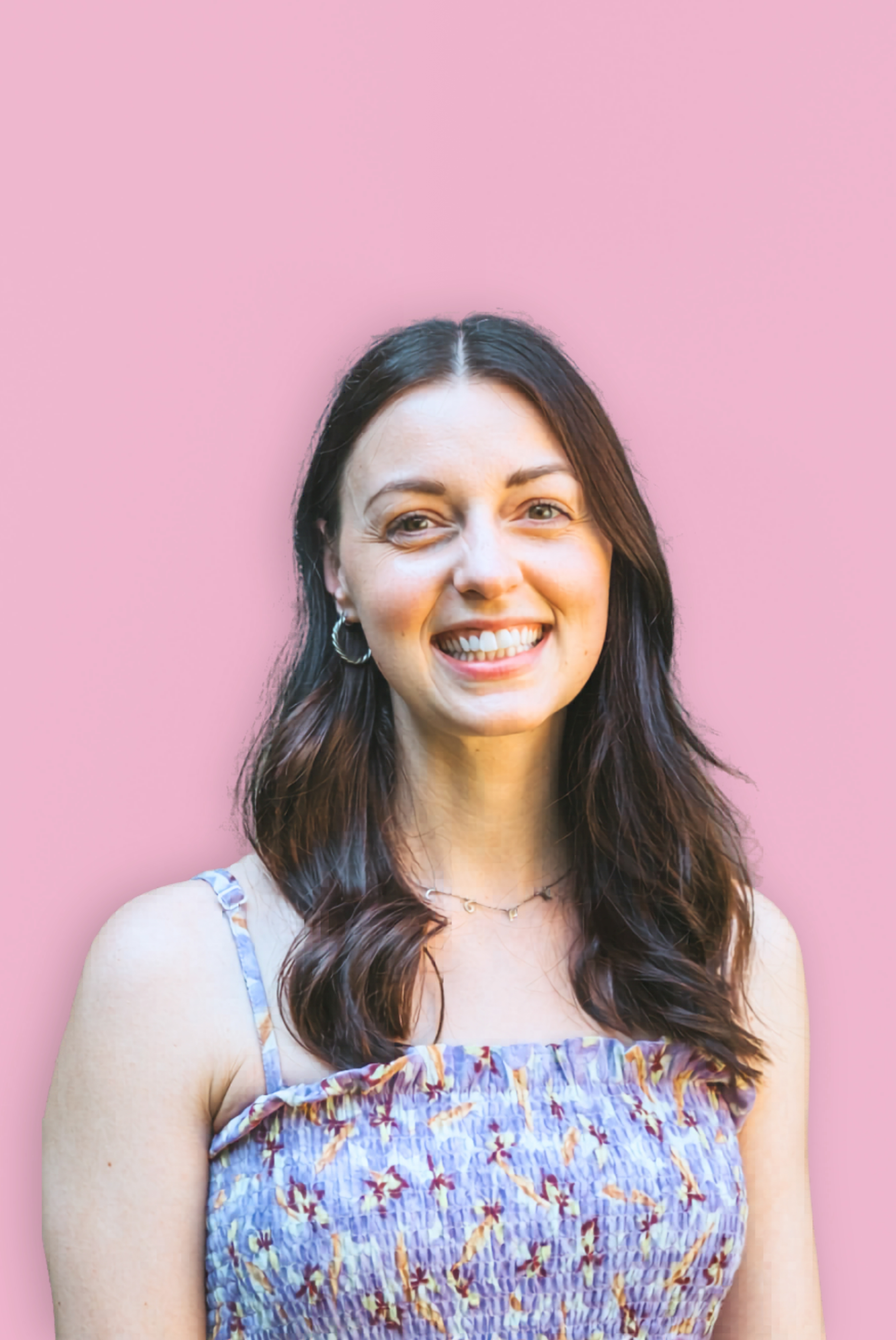 gemma humphreys, a woman with long brown hair smiles at the camera against a pink background