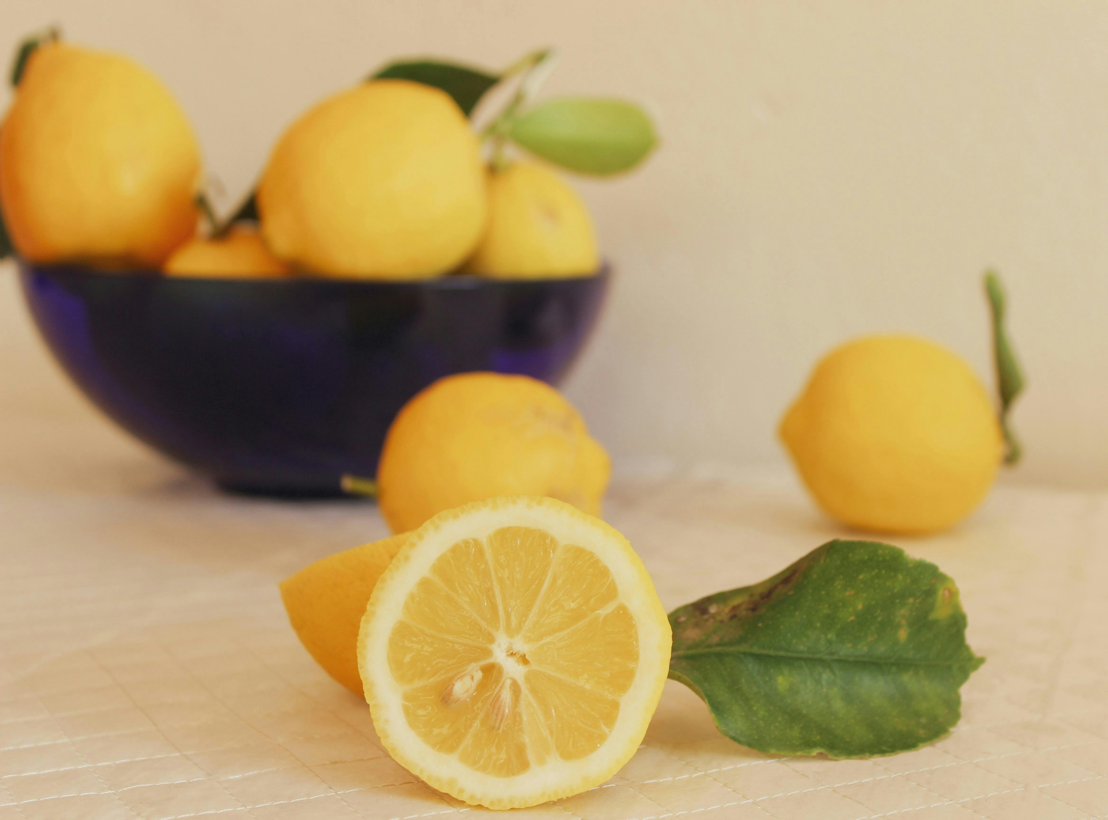 lemons in a bowl, with one cut in half to reveal the inside