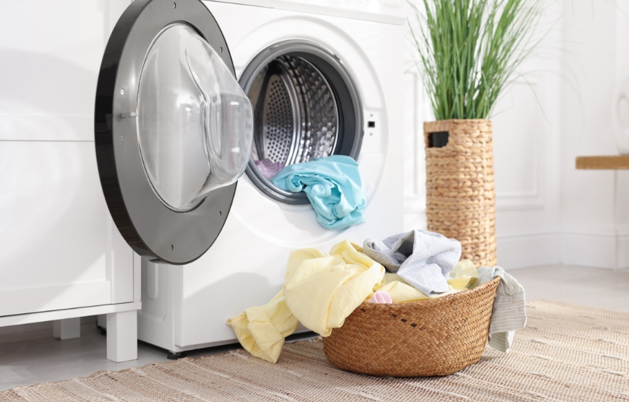 a white washing machine with laundry spilling out into a wicker basket