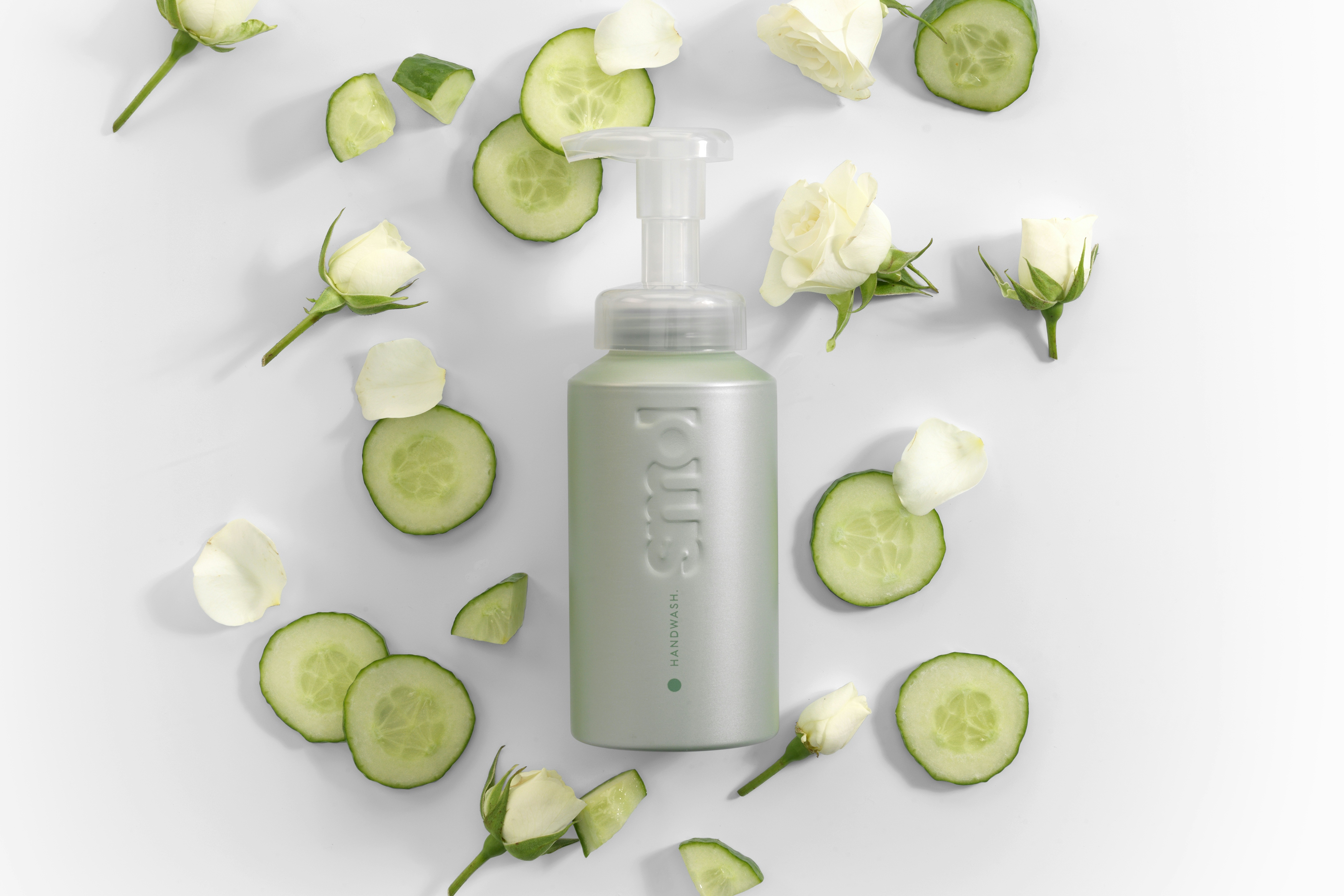 overhead image of smol foaming handwash pistachio aluminium bottle with cucumber slices and white roses and rose petals around the bottle