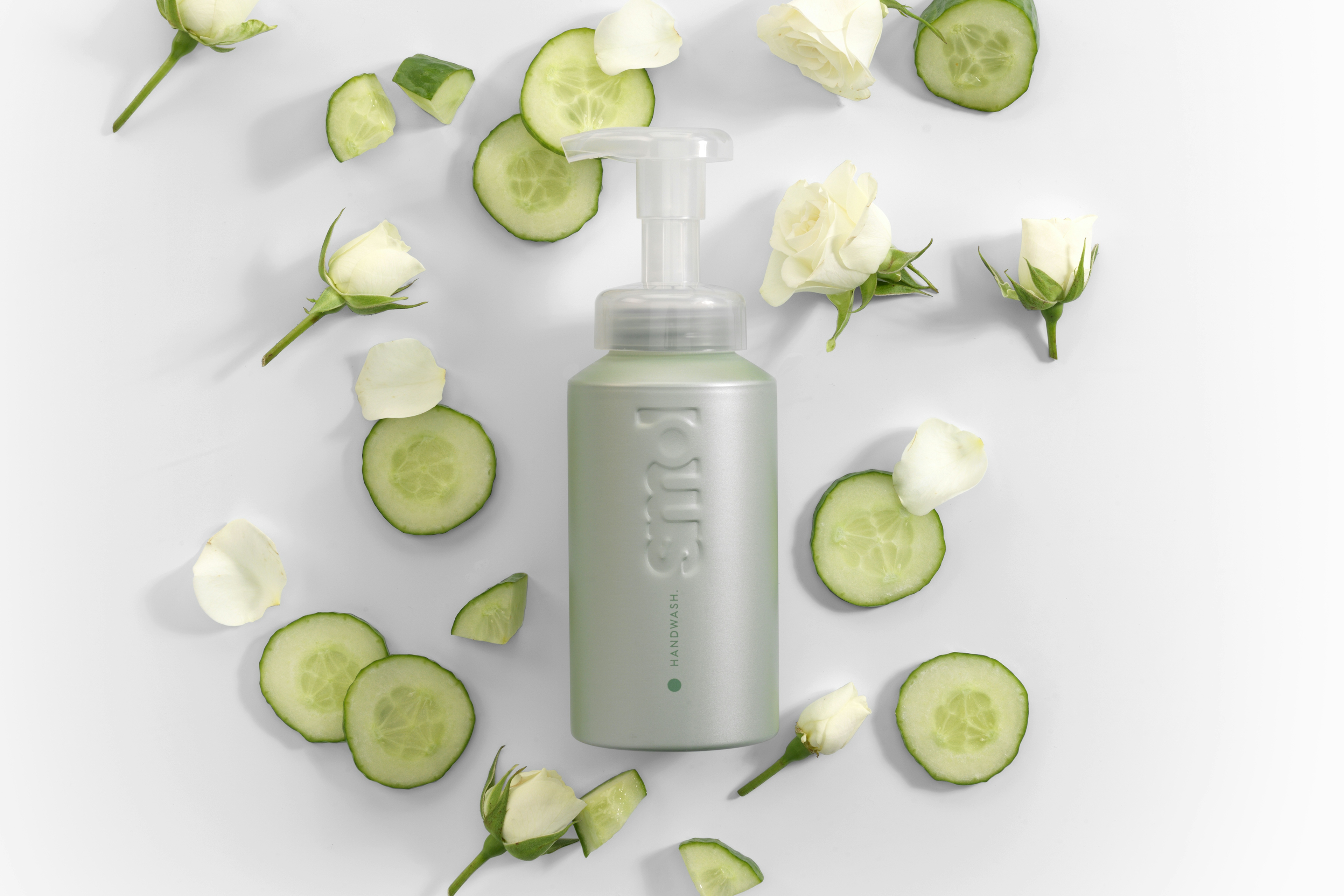 overhead image of smol foaming handwash pistachio aluminium bottle with cucumber slices and white roses and rose petals around the bottle