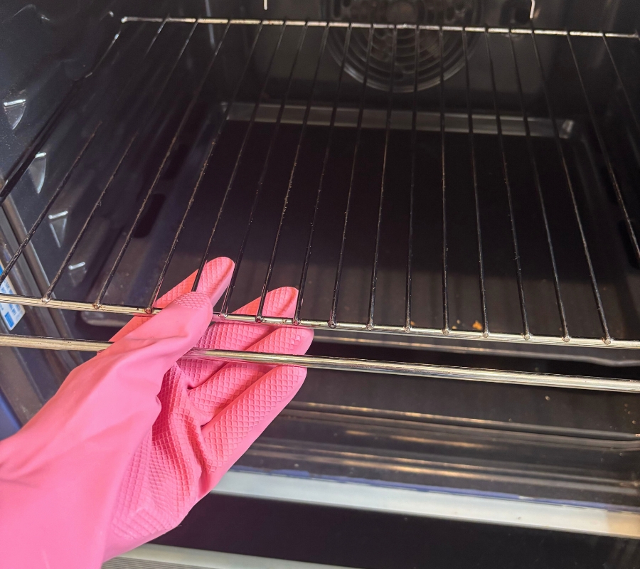 hands wearing smol rubber gloves taking oven shelves from oven