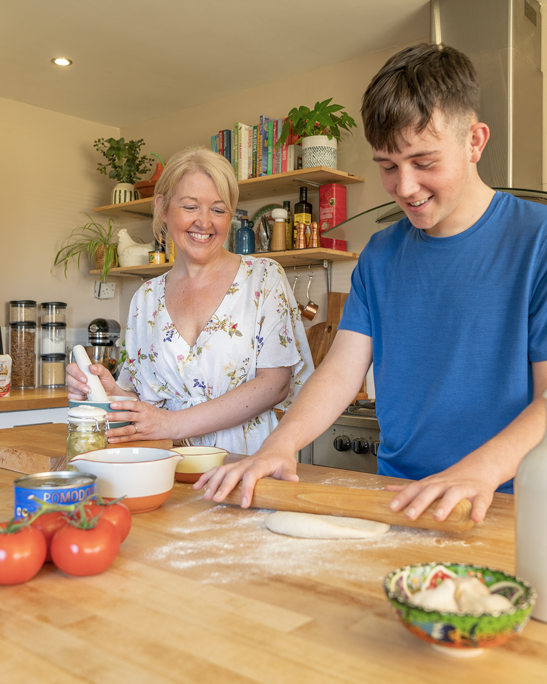 a mother and son smiling as they prepare food in the kitchen