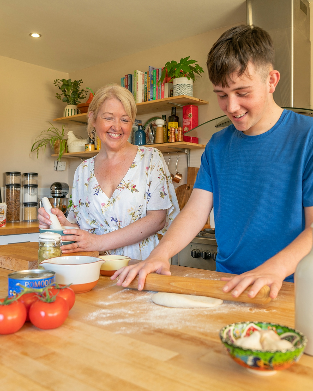 a mother and son smiling as they prepare food in the kitchen