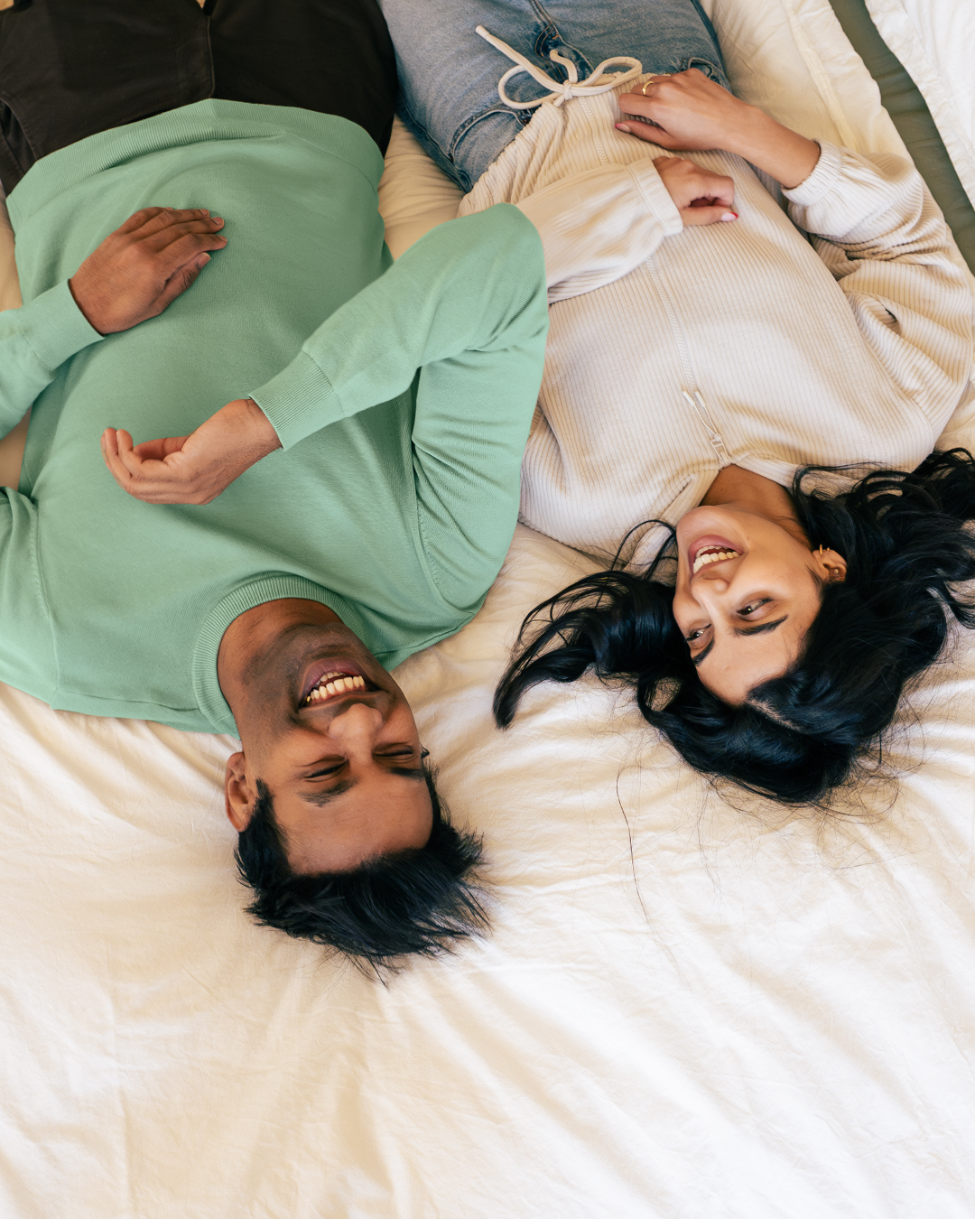 a bird's eye photo of a couple laying on a bed laughing