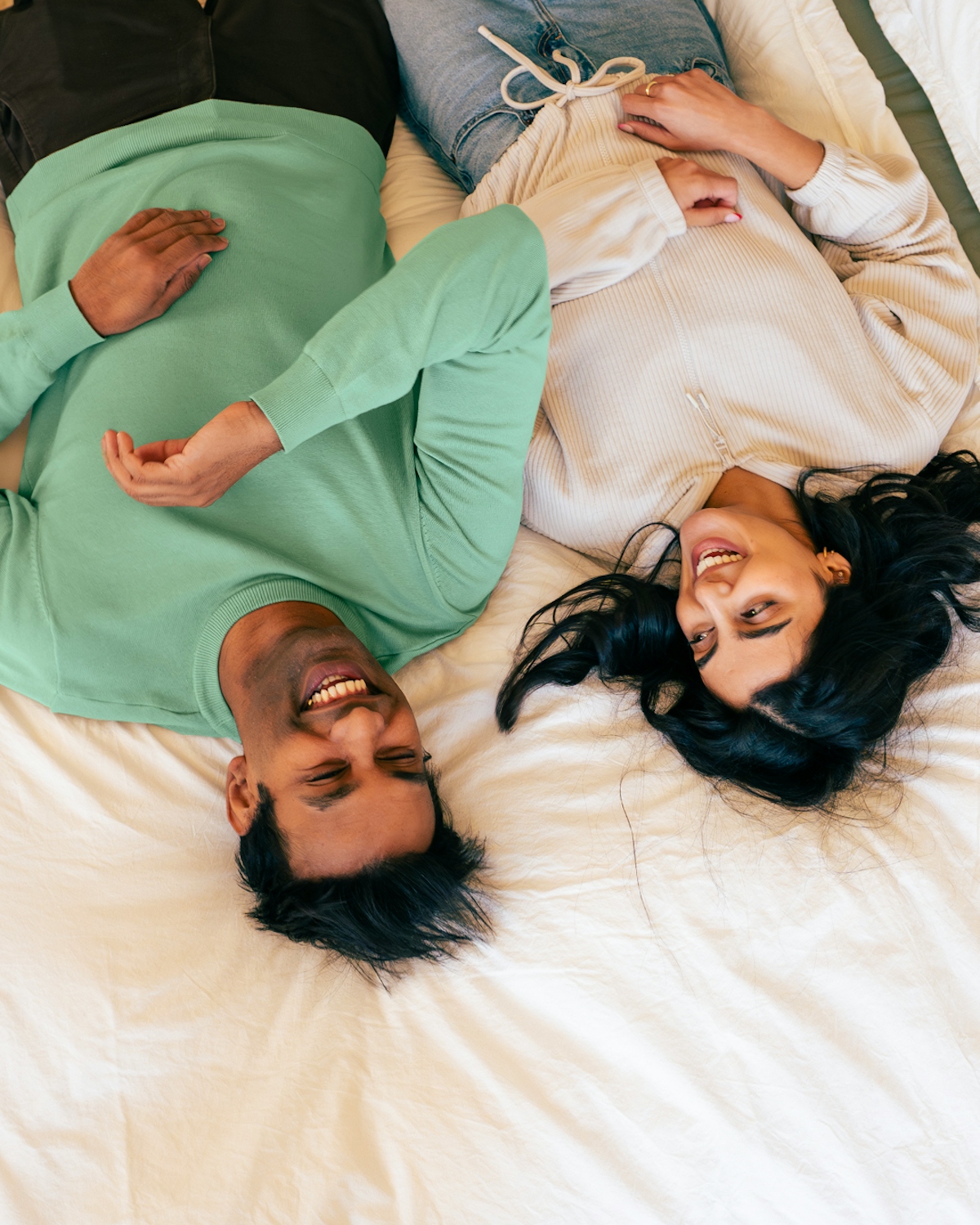 a bird's eye photo of a couple laying on a bed laughing