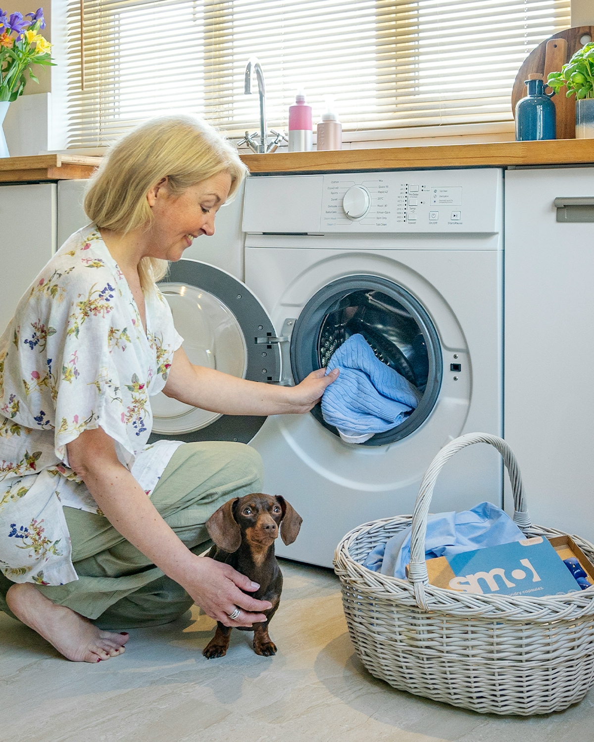 a woman putting her laundry in the washing machine using smol laundry capsules
