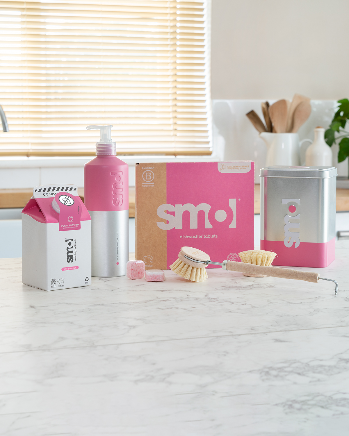 smol washing up liquid, dishwasher tablets, dishwasher tin caddy and dish brush on a kitchen counter