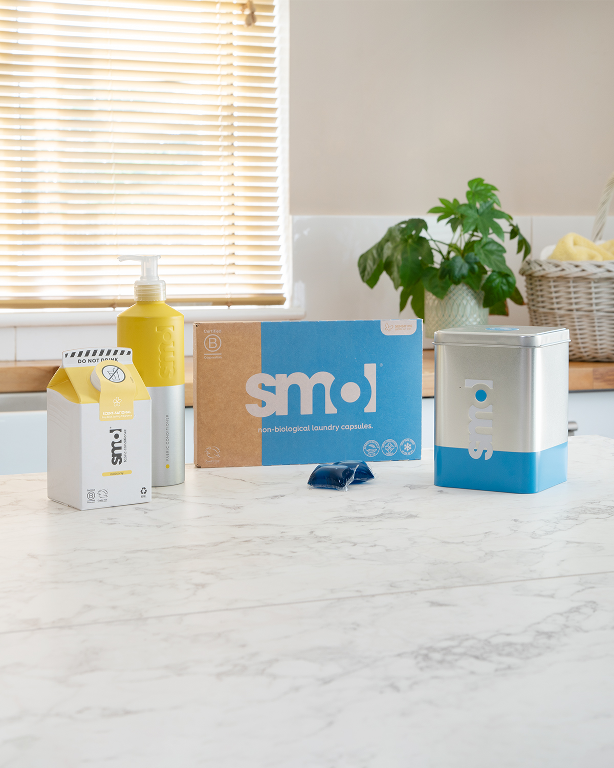 smol fabric conditioner, laundry capsules and laundry tin caddy on a kitchen counter