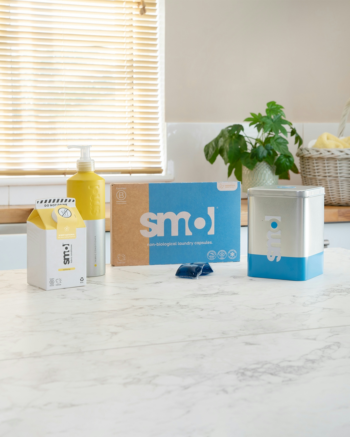 smol fabric conditioner, laundry capsules and laundry tin caddy on a kitchen counter